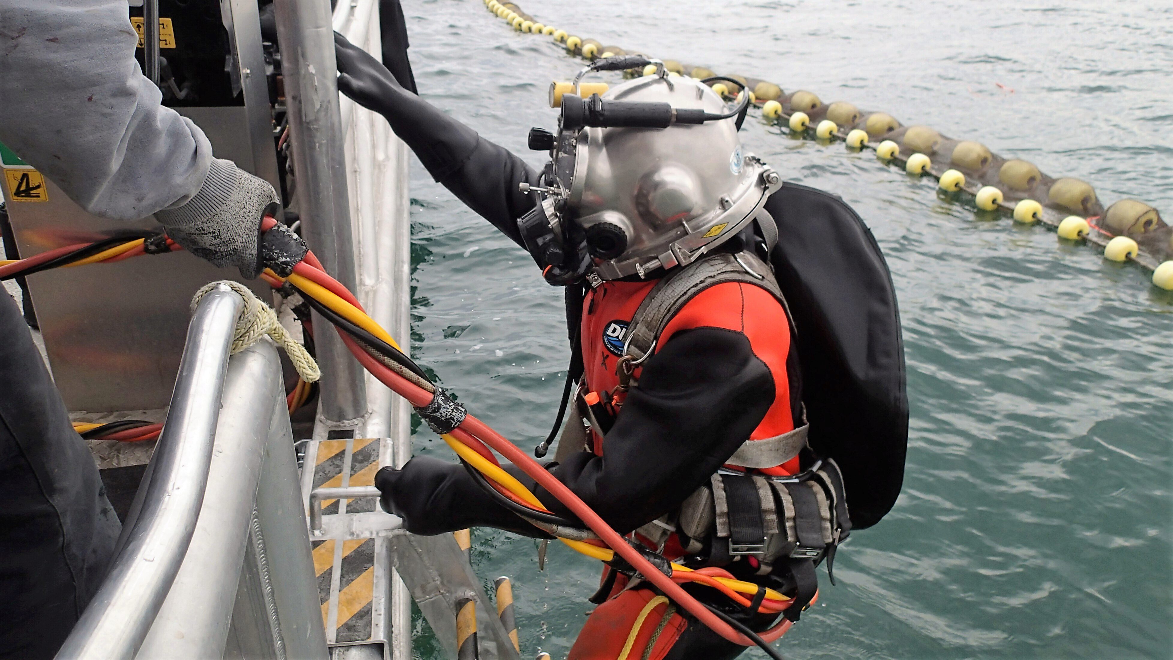 Man in scuba gear climbing out of water back onto the boat.