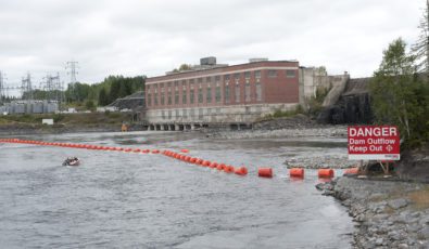 A motorboat approaches a water safety boom near our Alexander Generating Station.