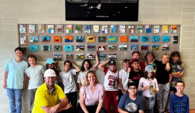 The Grade 4/5 class from Mattawa District Public School pose in front of their artwork at Otto Holden GS.