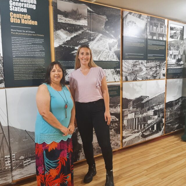 Judy Toupin, Curator of the Mattawa Museum, left, with Emily Salvalaggio, Senior Manager of OPG's Otto Holden and Des Joachims Generating Stations. Behind them is the museum's new exhibit on the Otto Holden Generating Station.