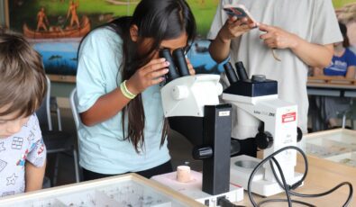 A participant peers through a microscope during the River Institute's pollinator workshop at OPG's Saunders Hydro Dam Visitor Centre.